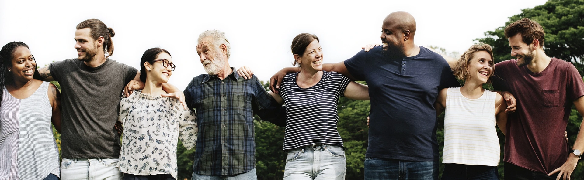 Groupe de personnes souriantes bras dessus bras dessous symbolisant la diversité et l’esprit d’équipe